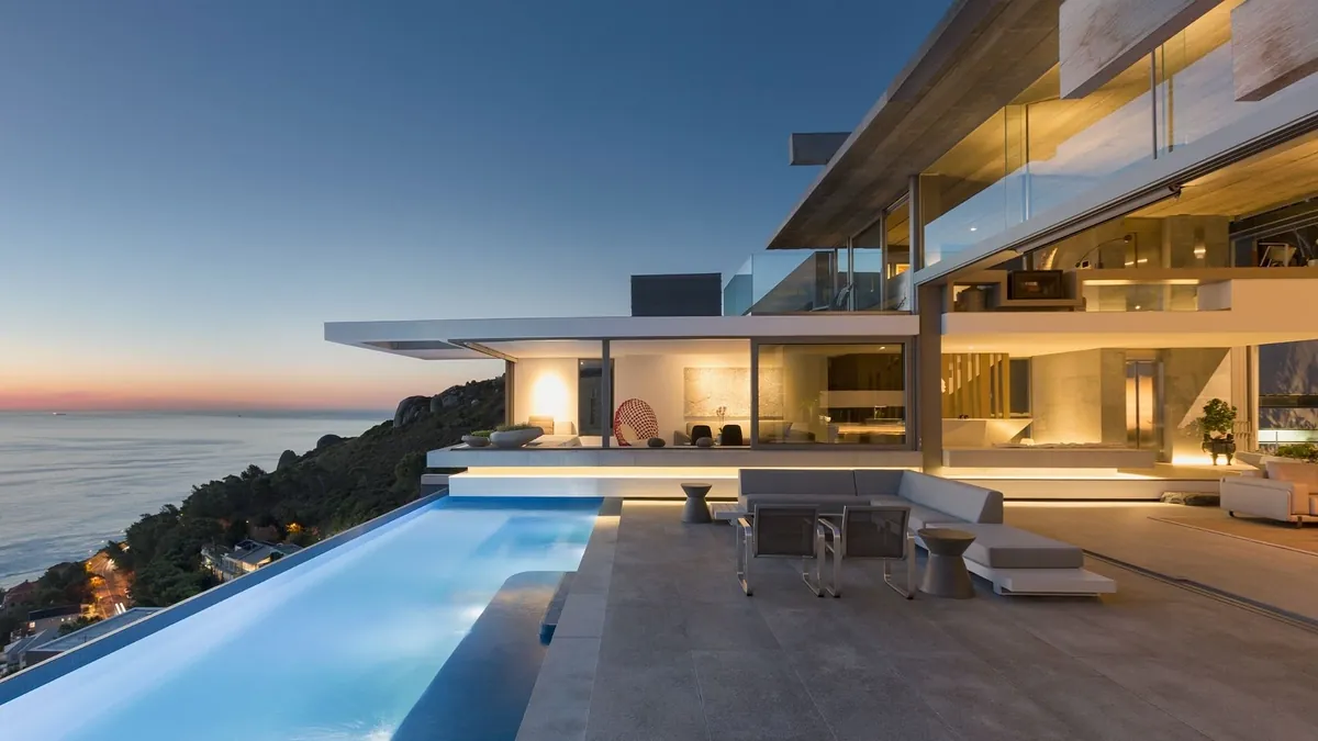 A modern house cantilevered over the sea at dusk